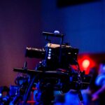 A high-quality camera setup capturing a live studio event with an audience in the background.